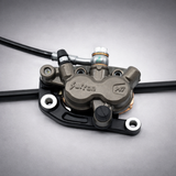 Sur-Ron Ultra OEM hydraulic brake caliper mounted on bracket — heavy-duty replacement caliper for electric dirt bikes